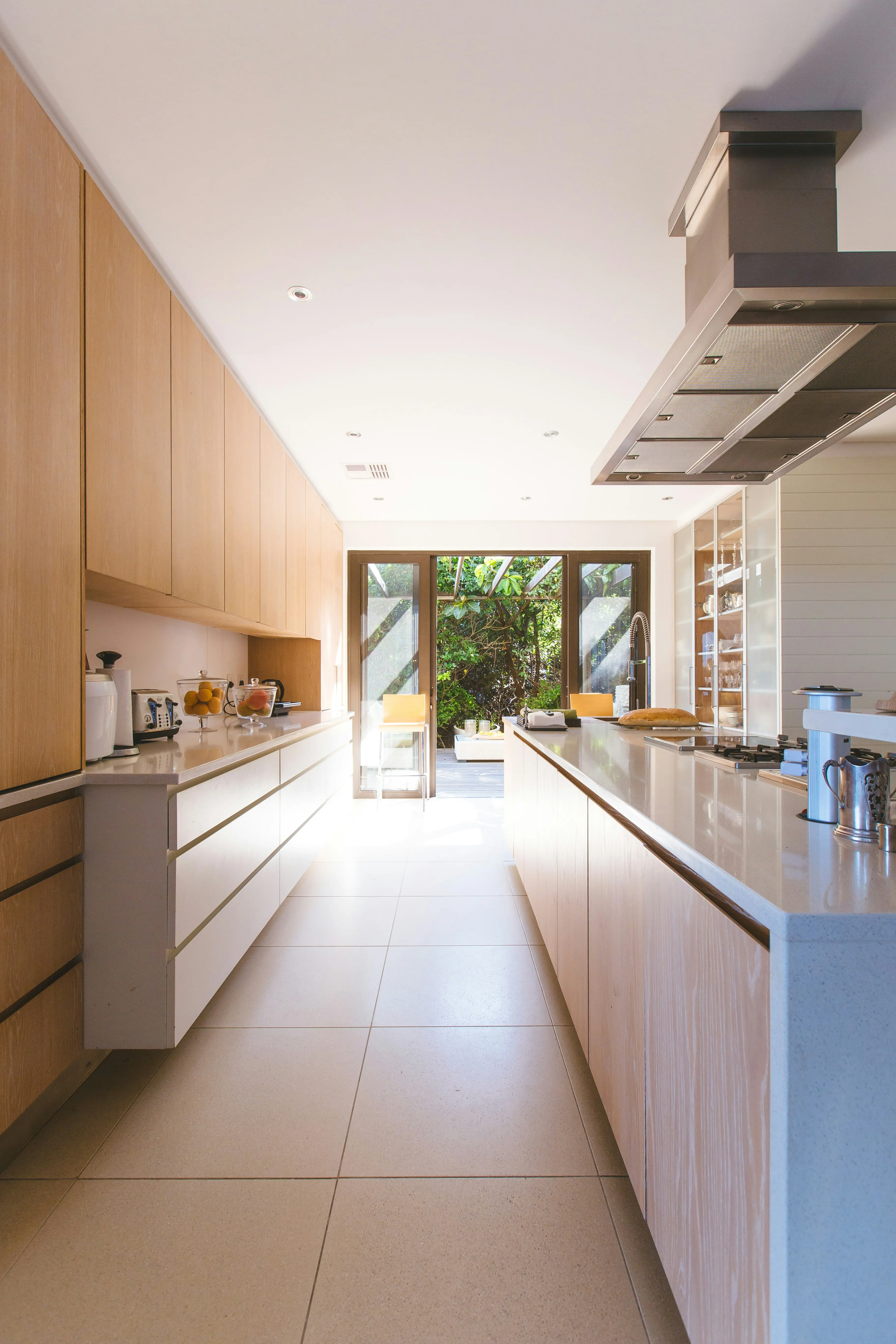 Stunning modern kitchen remodel by LA Enterprises with natural wood cabinetry, sleek countertops, and beautiful garden view through large windows
